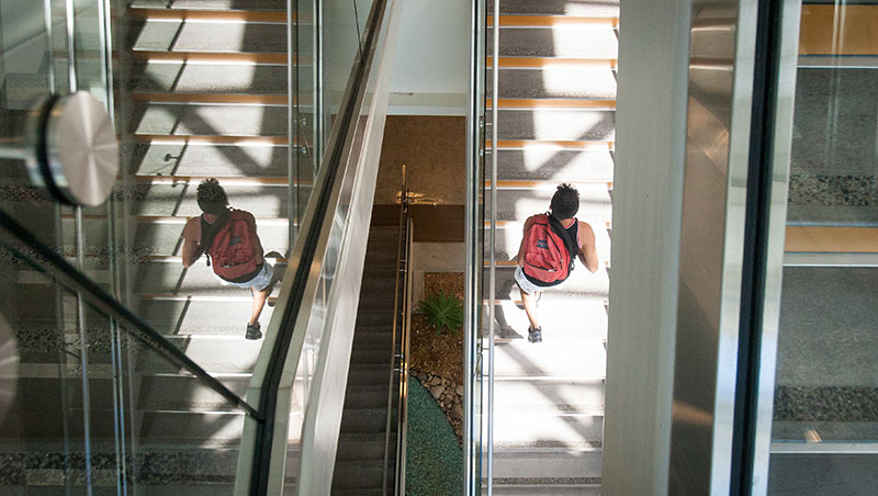 A top-down view of a student traversing the glass and steel SAS building staircase