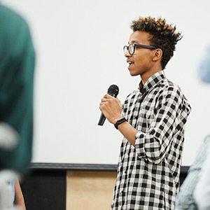 A student gives a presentation while holding a microphone