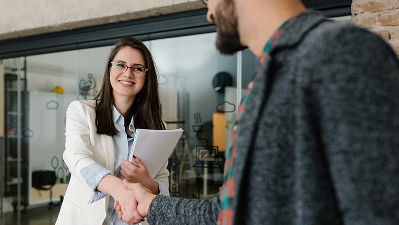 A human resource professional shakes the hand of an applicant