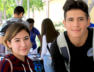Two students stand at a transfer fair table