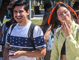 Two students laugh while walking around campus