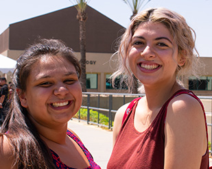 Two young women students smile at the camera in Coudures Plaza