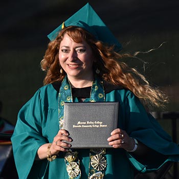 A graduate holds up their degree