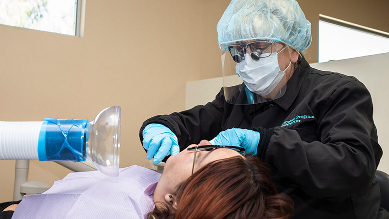 A dental hygiene faculty member works with a patient