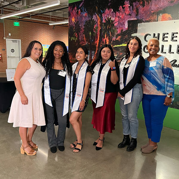 A group of College Corps Fellows wearing sashes stand with Moreno Valley City Councilmember Elena Baca Santa Cruz and Moreno Valley College Professor Frankie Moore.