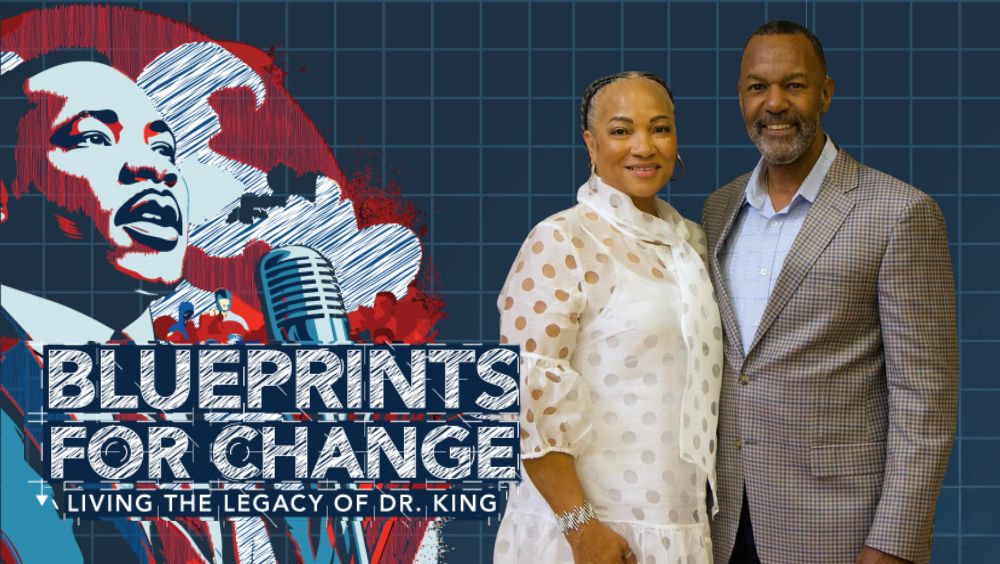 Portrait of L. Kirk Sykes and Karen Sykes in front of event marketing design