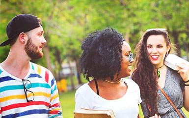 Three students cross a park lawn