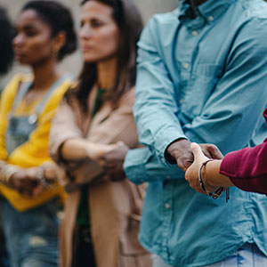 Diverse individuals hold hands to create a human chain