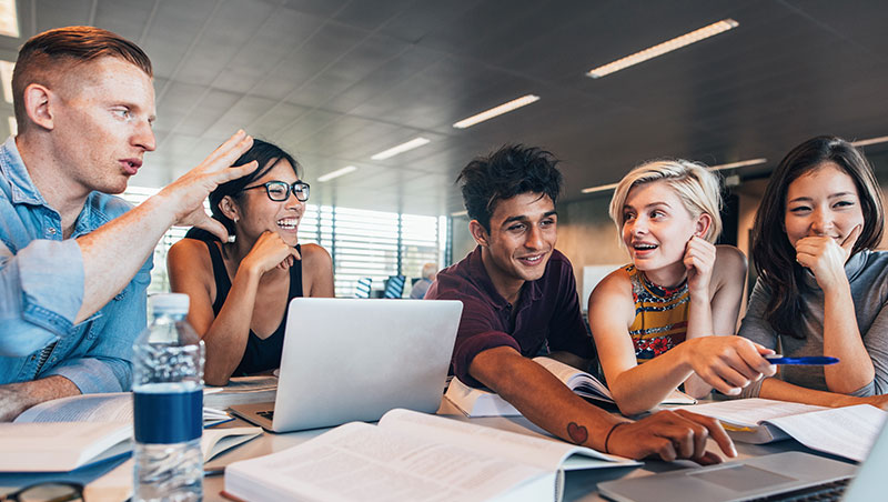 A group of students collaborate together while smiling