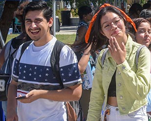 Two students grin as they walk across campus