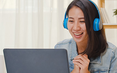 A student smiles while talking to a Student Services staff person on their laptop