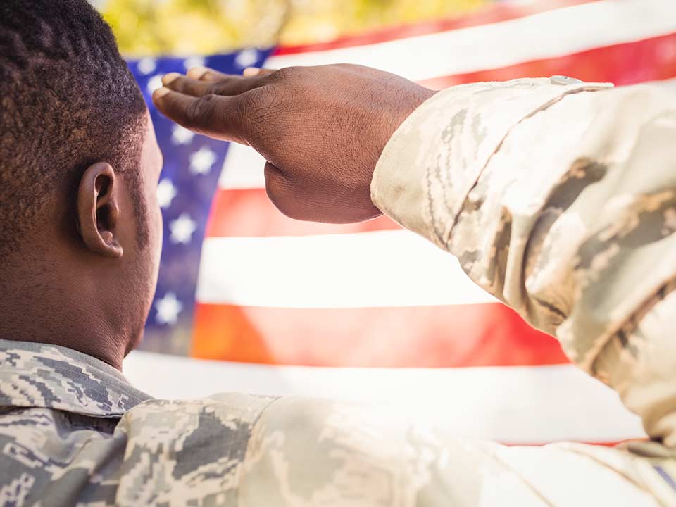 A veteran in fatigues salutes the US flag